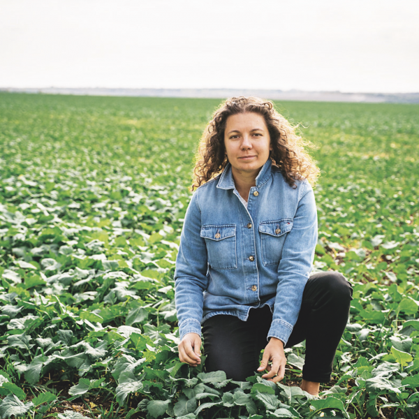 CRDC-supported innovator Anastasia Volkova of Regrow Ag kneeling in a cotton field.